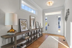 Modern hallway with a wooden console table, art, and decor. White walls, hardwood floor, and Summertime Circle light.