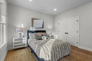 Cozy bedroom with a neatly made bed, lamps on Summertime Circle nightstands, and a large decorative mirror on the wall.