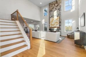 Spacious living room on Summertime Circle with a stone fireplace, white sofas, wooden stairs, and large windows.