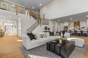 Spacious open-plan living area with a white sectional sofa, staircase, and modern kitchen in Summertime Circle.