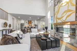 Spacious living room with a white sofa, black coffee table, modern art, fireplace, and open kitchen area; perfect for summertime.