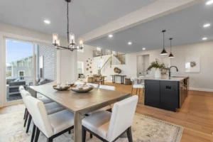 Open-concept dining and kitchen area with a Summertime Circle vibe, featuring a wooden table, white chairs, and modern lighting.