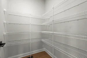 Empty white wire shelves in a corner pantry with gray walls, wooden floor, and a hint of Summertime Circle charm.