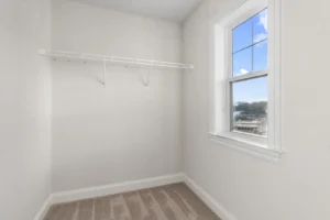 A small, empty closet with a window and a white wire shelf, featuring beige carpet and white walls on Summertime Circle.