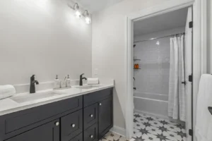 A modern bathroom on Summertime Circle features a double sink vanity, black cabinets, and a tiled shower with a white curtain.