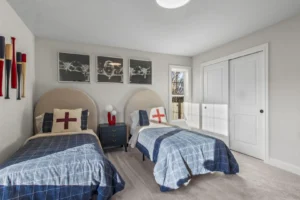 Bedroom at 5 Summertime Circle: twin beds, blue plaid bedding, red cross pillows, and minimalist decor.