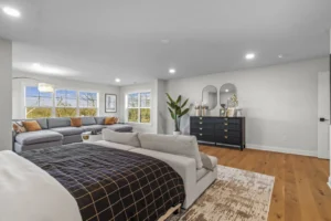 Spacious Summertime Circle living room with gray sofas, a bed, large windows, and a black dresser topped with mirrors.