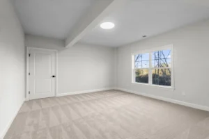 Empty room with beige carpet, white walls, a single door, and a large window offering views of Summertime Circles trees.