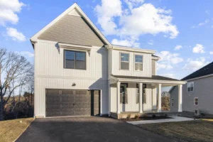 Modern two-story house on Summertime Circle, featuring a gray facade, large windows, and an attached garage against a clear sky.