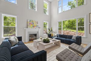 A bright living room with large windows, a fireplace, blue sectional sofas, a coffee table, and modern decor.