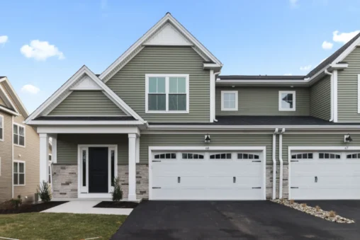 Modern two-story house on Soderman Way with green siding, two white garage doors, and a neatly landscaped front yard.